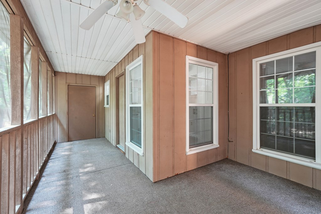 A large screened-in patio with storage and a ceiling fan.
