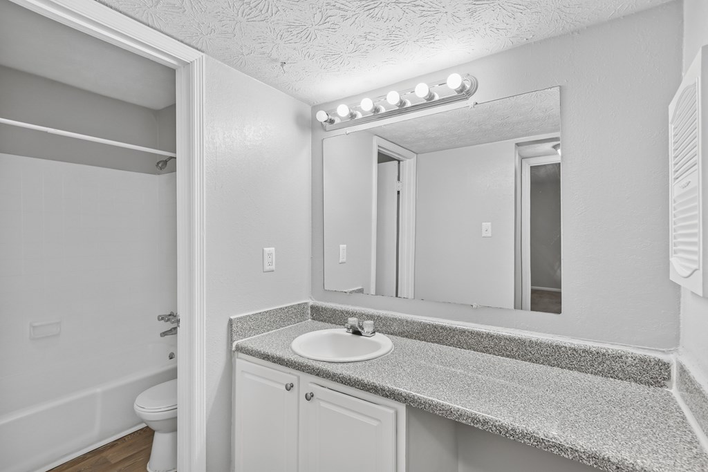 A bathroom with a sink, mirror, and lights.