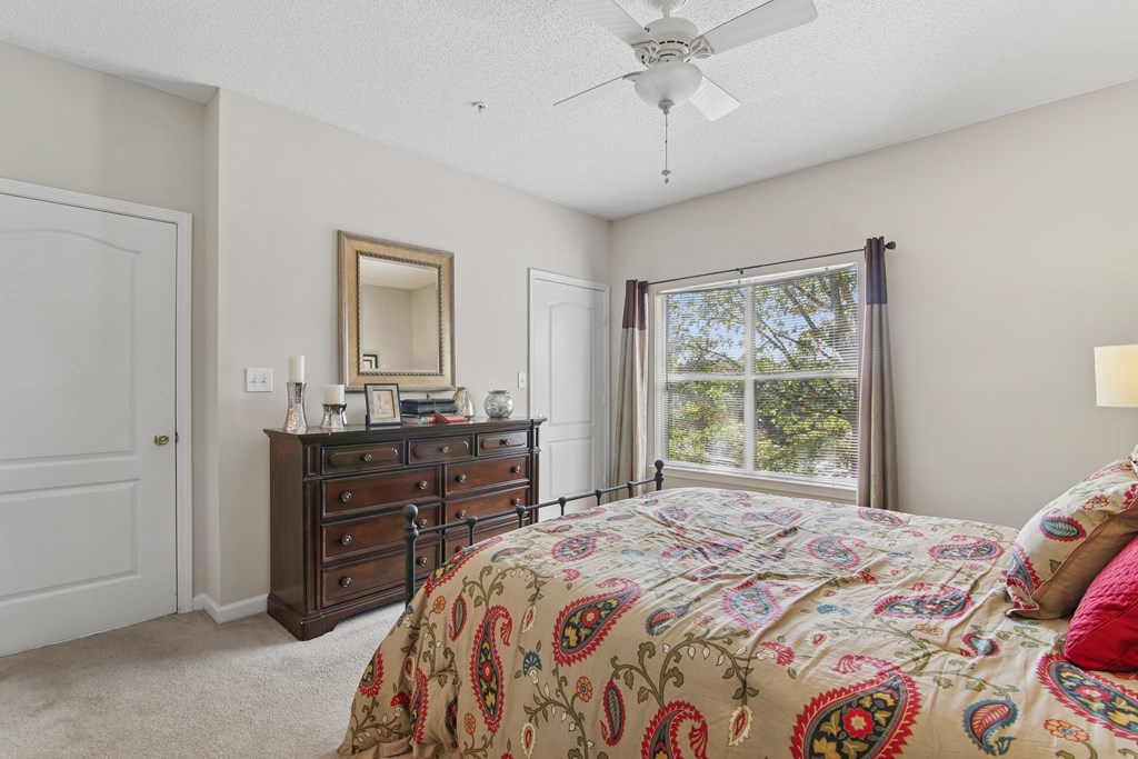 Bedroom with a bed, dresser, mirror, and window.