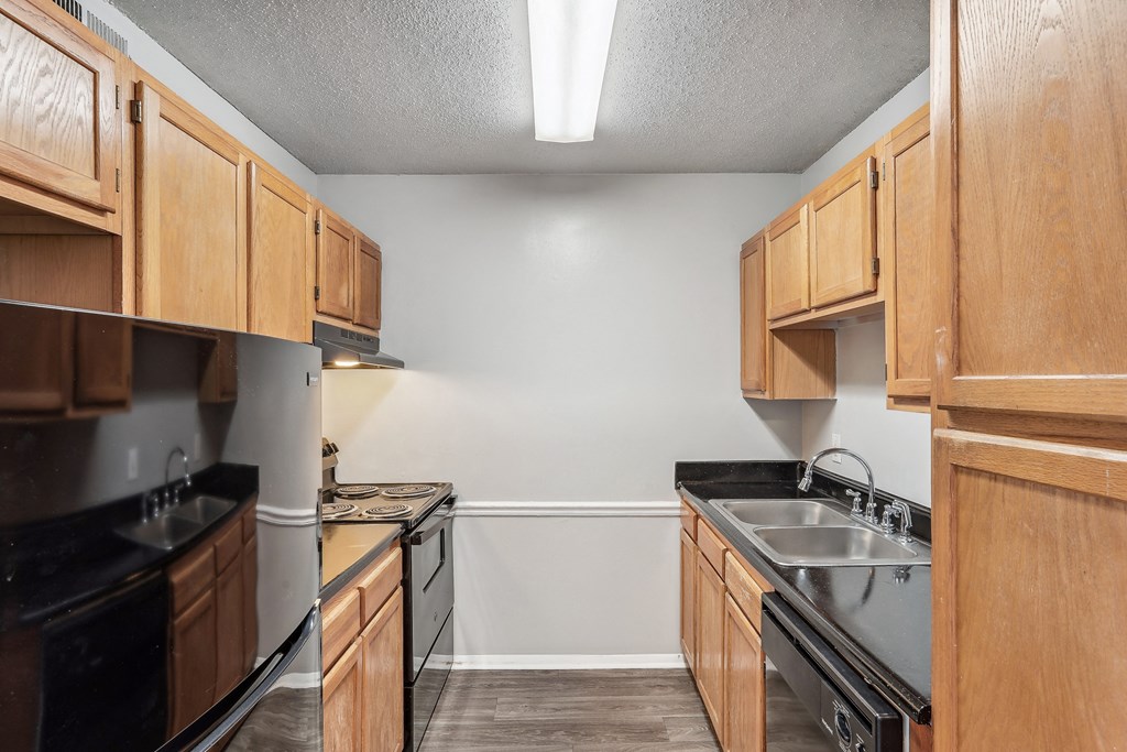 an empty kitchen with wooden cabinets and black appliances