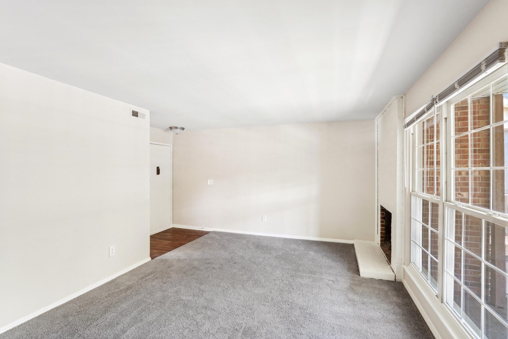 an empty living room with large windows and a carpet