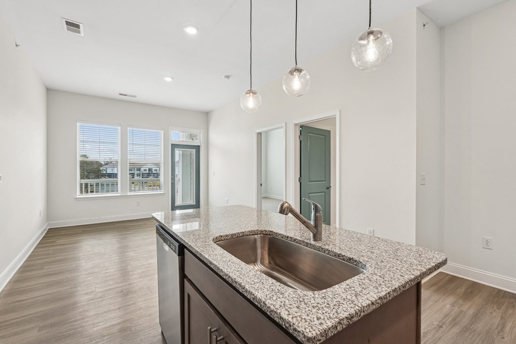 A kitchen with a granite countertop and a stainless steel sink.at The Parker Leland, Leland, NC  