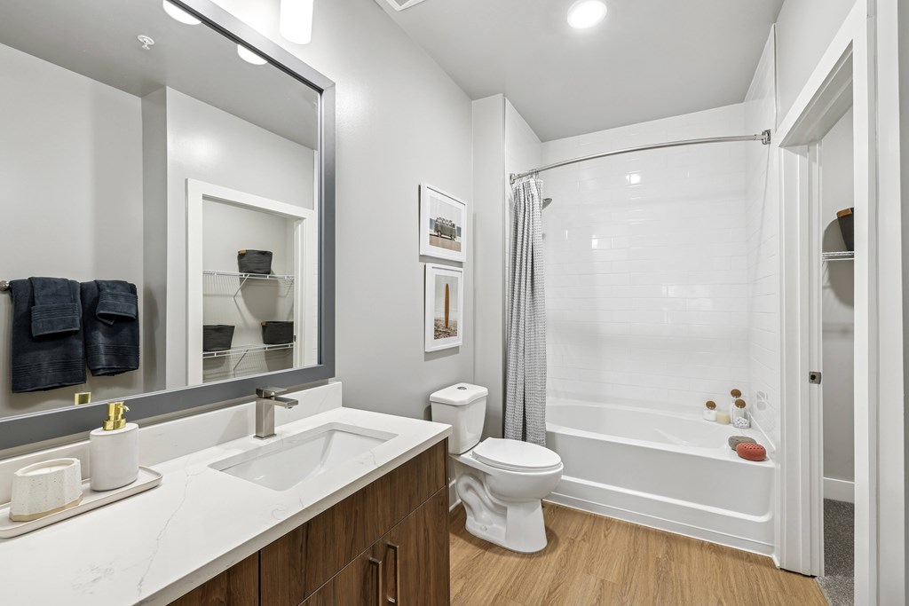 A white bathroom with a toilet, sink, and mirror.at The Exchange at Crestview Apartments, Crestview, Florida
