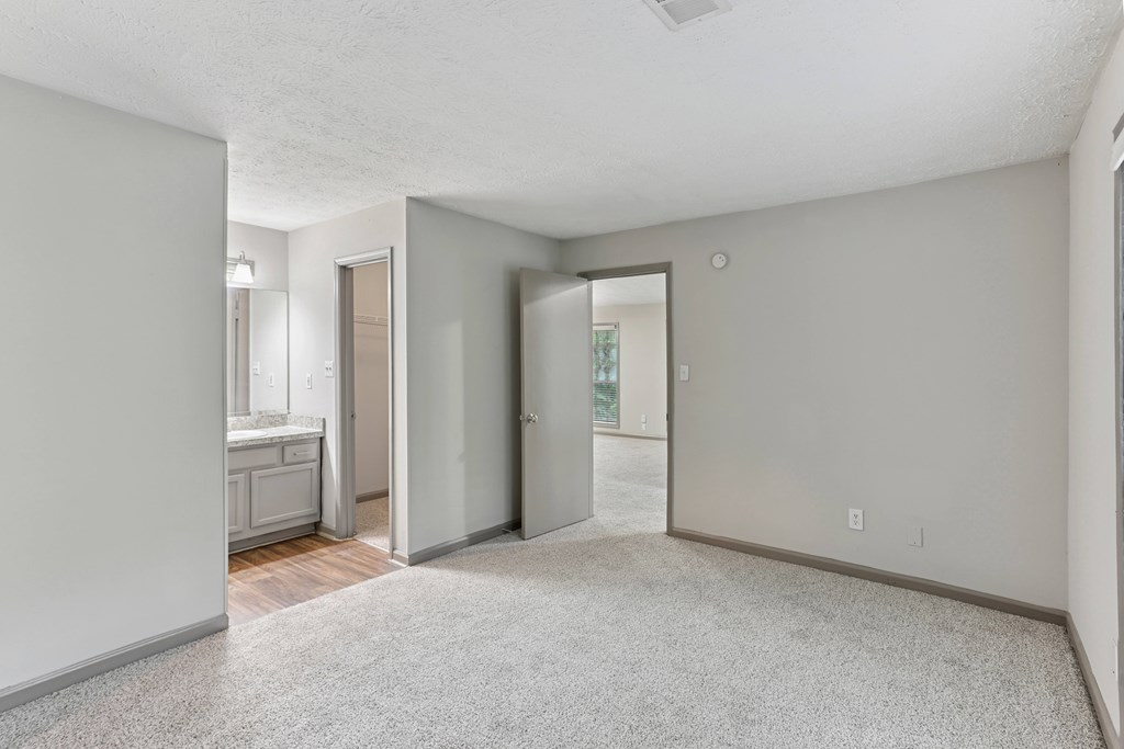 A spacious room with a carpeted floor and a door leading to a balcony.