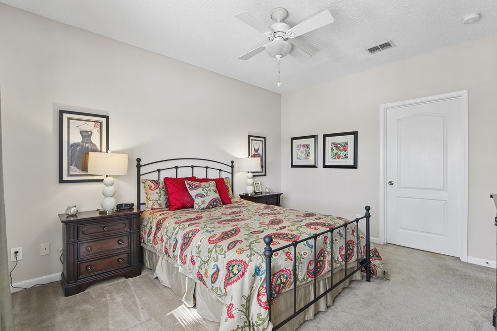 A bedroom with a bed, dresser, and ceiling fan.