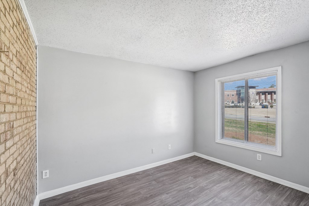 the living room of an apartment with a window and wood flooring