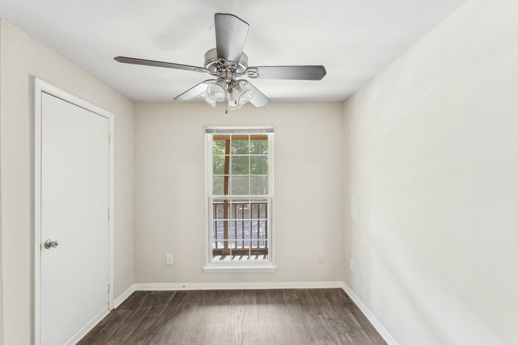 an empty room with a ceiling fan and a window