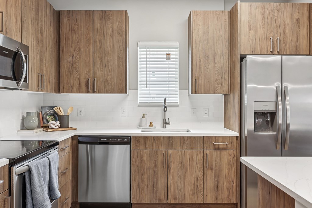 A modern kitchen with wooden cabinets and stainless steel appliances.at The Exchange at Crestview Apartments, Crestview, FL
