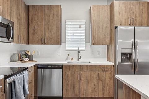 A modern kitchen with wooden cabinets and stainless steel appliances.at The Exchange at Crestview Apartments, Crestview, FL