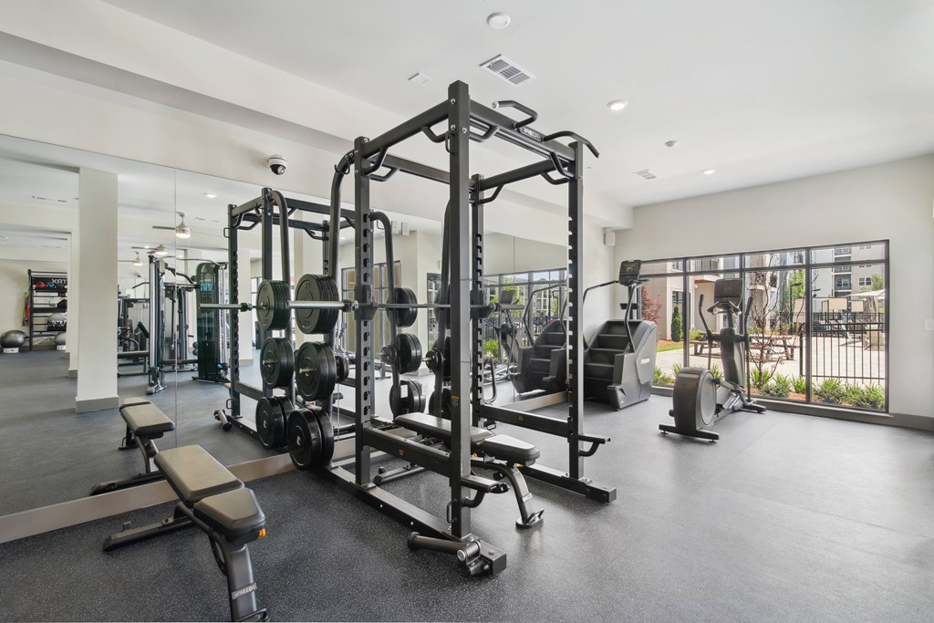 A gym with a variety of equipment including a squat rack.at The Delaney at East Park Apartments, Kennesaw, 30144