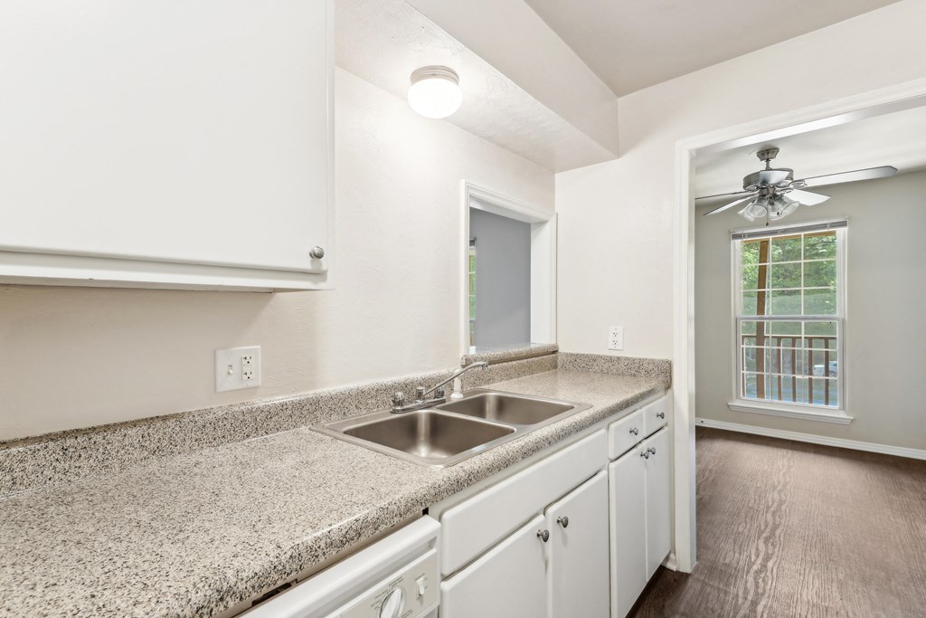 a kitchen with white cabinets and granite counter tops and a sink