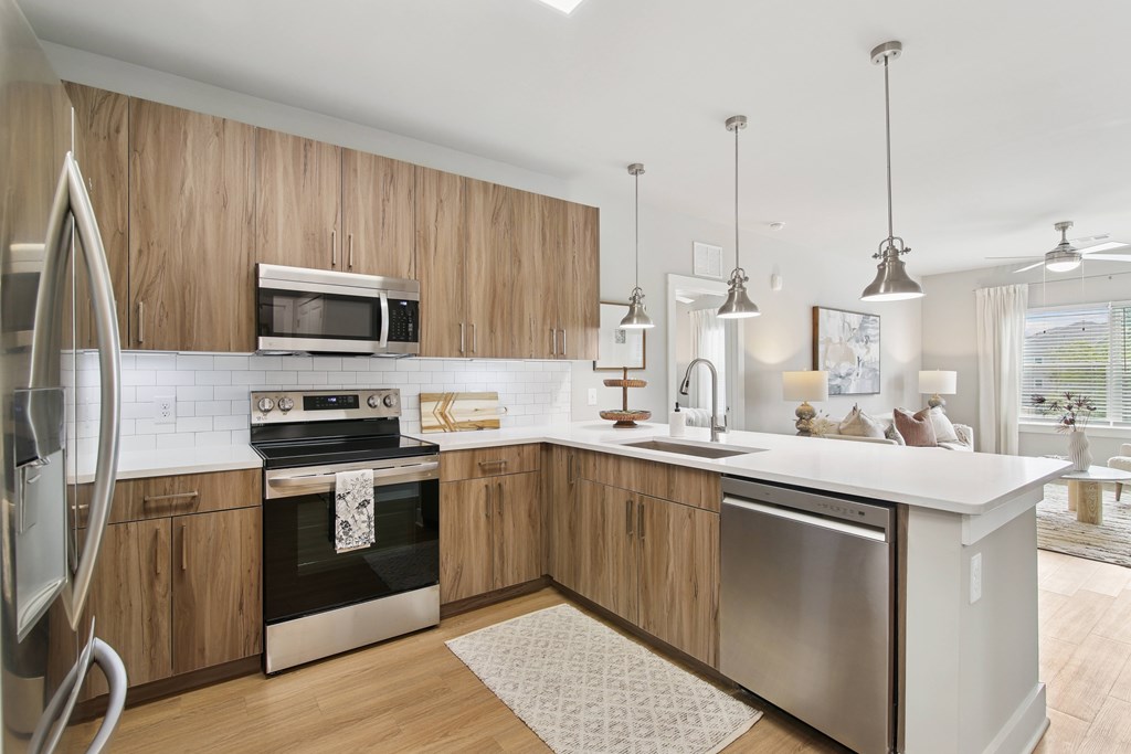 A modern kitchen with wooden cabinets and stainless steel appliances.at The Delaney at East Park Apartments, Kennesaw, Georgia