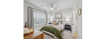 A bedroom with a bed, nightstand, and window.