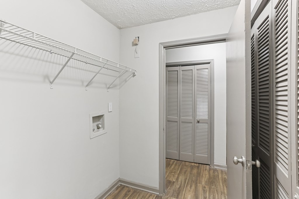 A white room with a door and a shelf.
