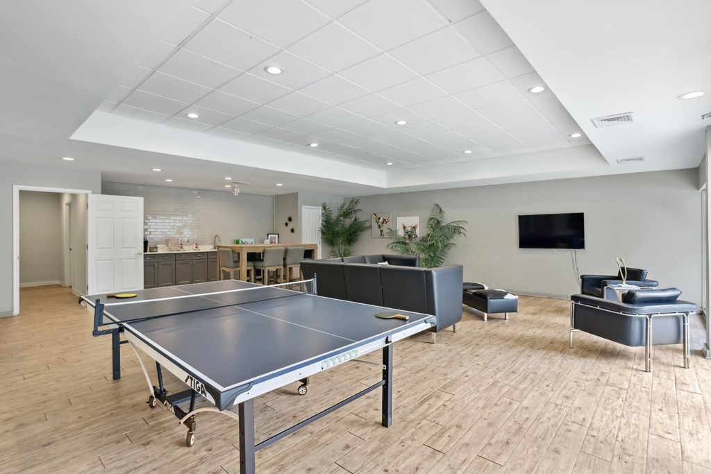 A ping pong table is in the middle of a room with a tv and a couch.