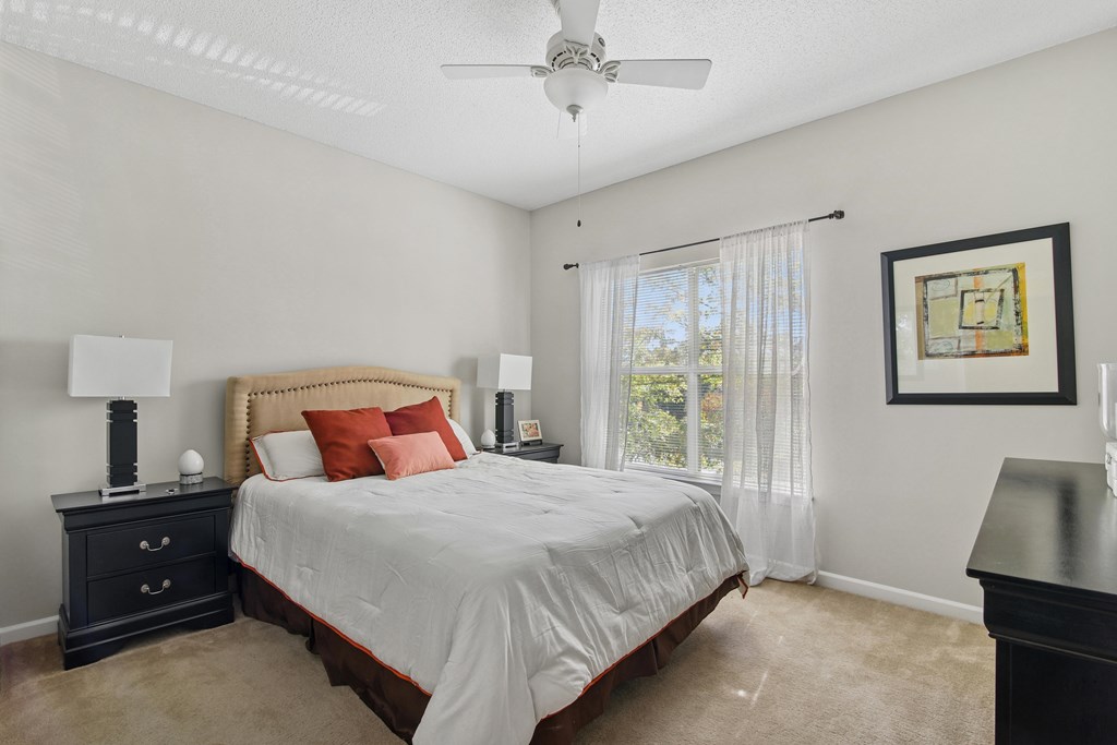 A bedroom with a bed, nightstand, and a ceiling fan.