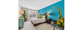 A bedroom with a bed, a chair, and a large green sculpture.