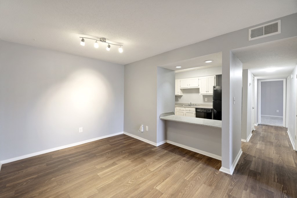 the living room and kitchen of an apartment with wood flooring and white walls  at Governors House, Huntsville