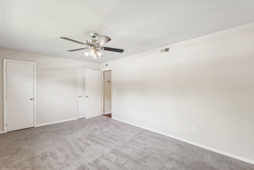 an empty living room with carpet and a ceiling fan