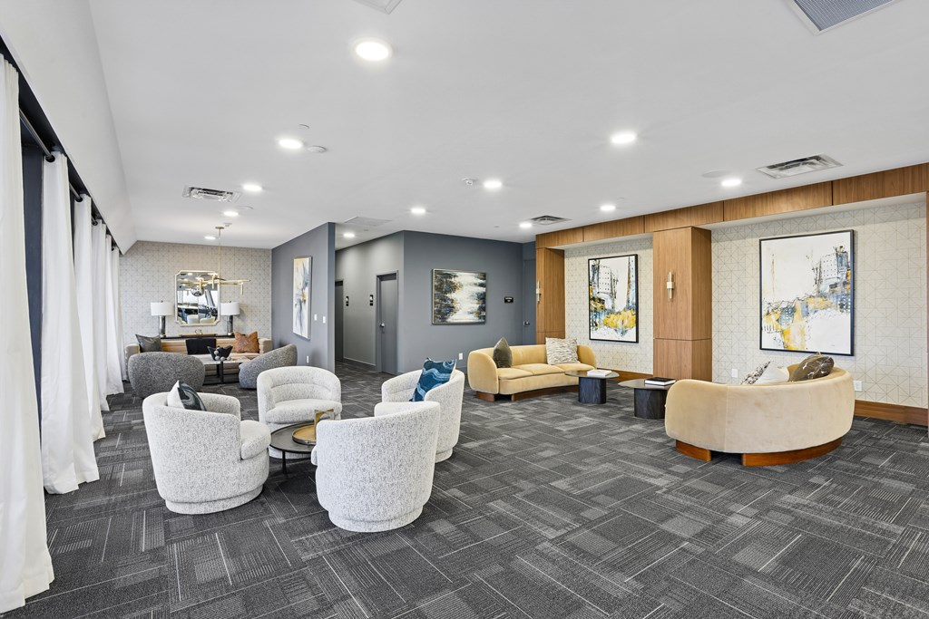A spacious waiting area with grey carpet and white chairs.