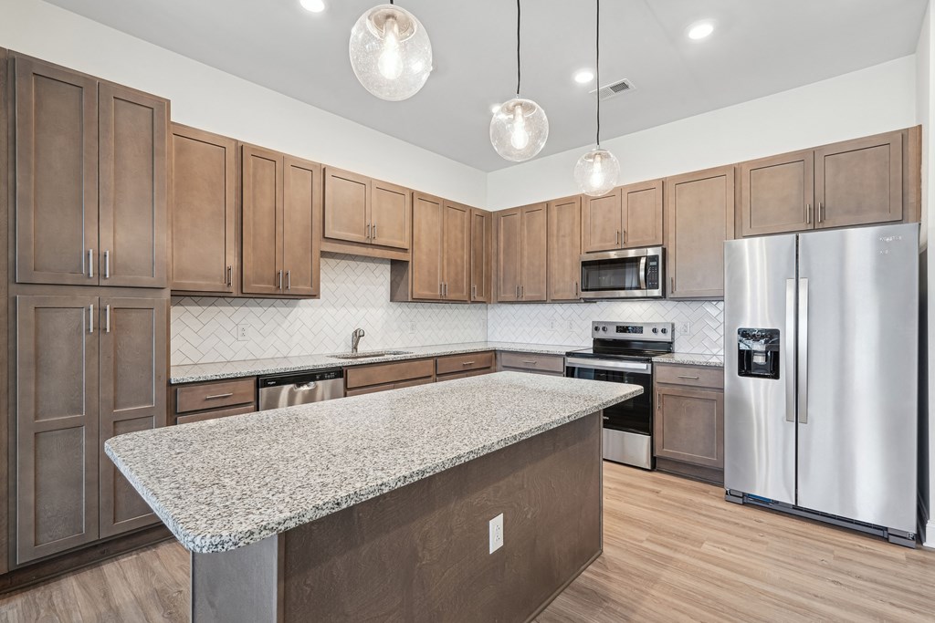 A kitchen with wooden cabinets and a granite countertop.at The Parker Leland, North Carolina  