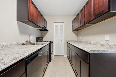 A kitchen with dark brown cabinets and granite countertops.