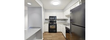 A kitchen with black appliances and white cabinets.