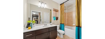 A bathroom with a white sink and brown cabinets.