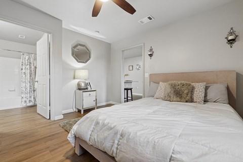A bedroom with a large bed and a ceiling fan.