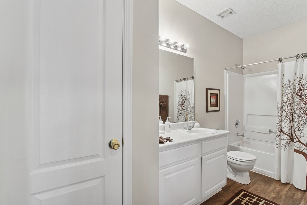 A white bathroom with a toilet, sink, and mirror.