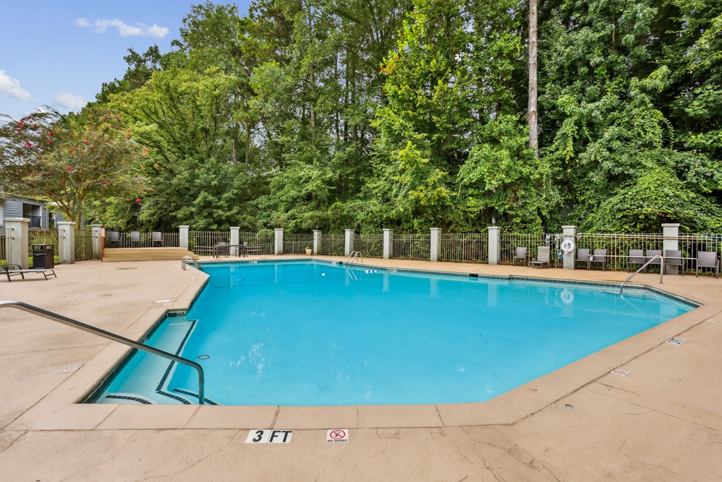 A small pool surrounded by a fence and trees.