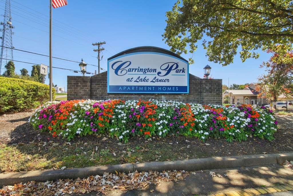 A sign for Carrington Park at Lake Lea Lure with a flower bed in front.