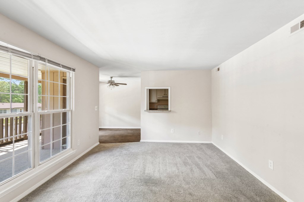 an empty living room with a window and a ceiling fan