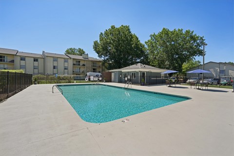 A swimming pool in a sunny day surrounded by apartment buildings.