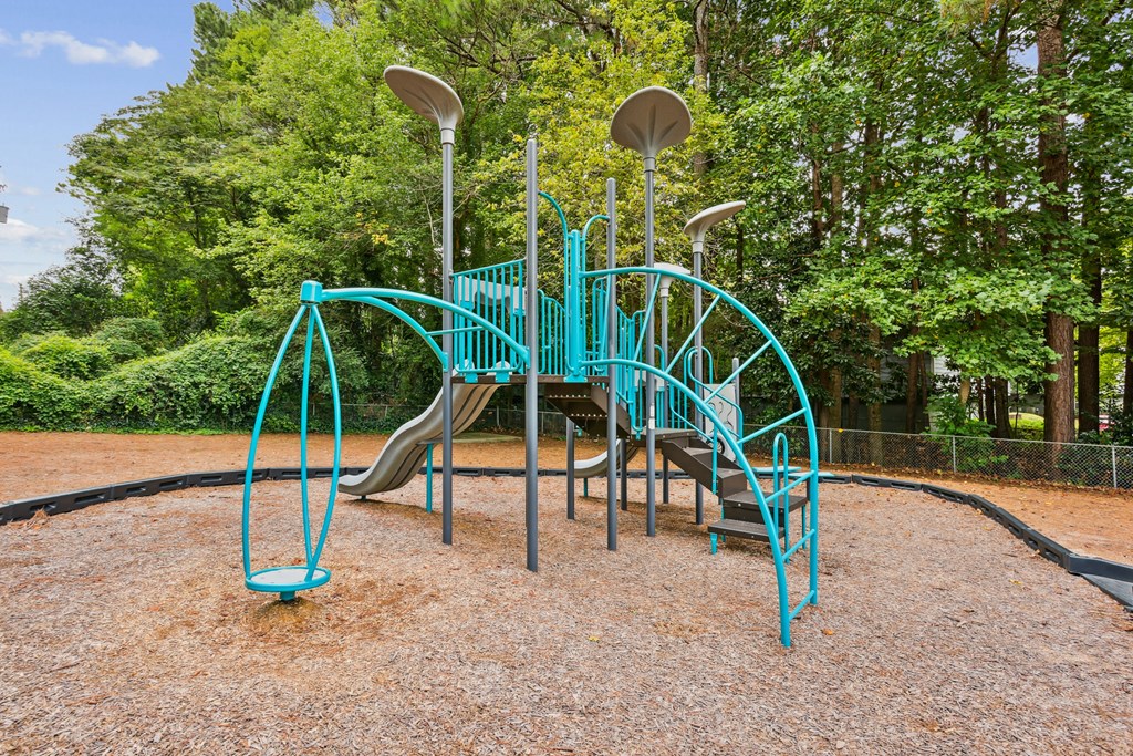 A playground with a teal slide and a brown ground.