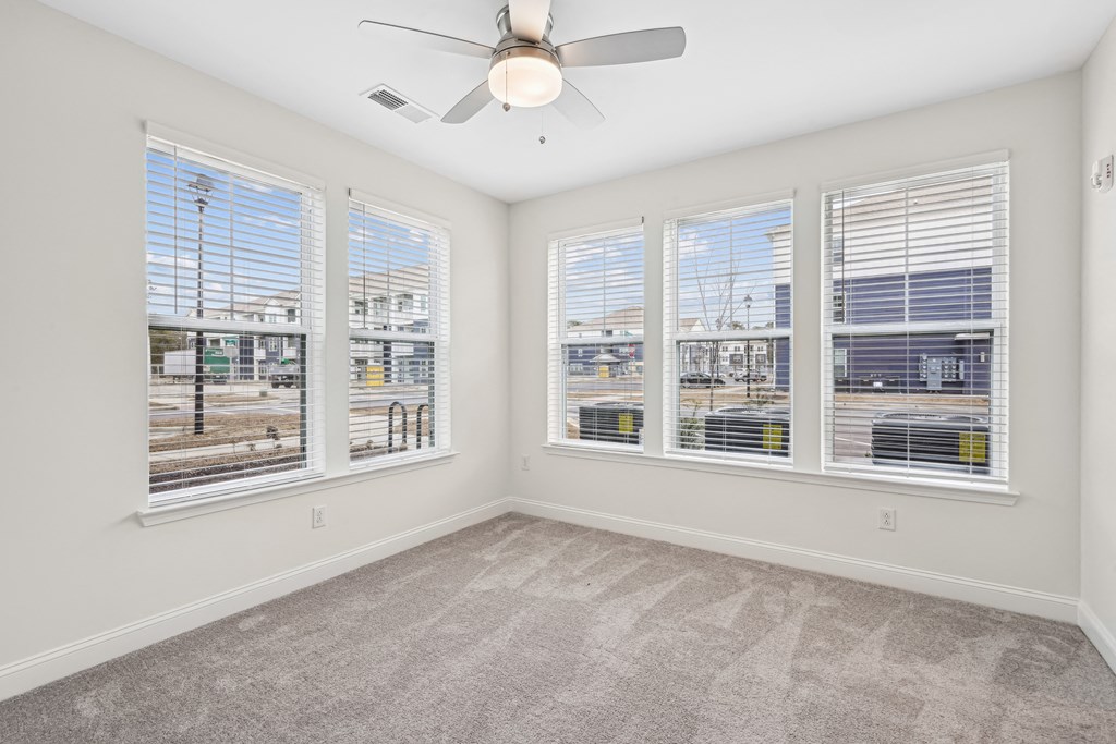 A room with a ceiling fan and three windows.at The Parker Leland, Leland North Carolina  
