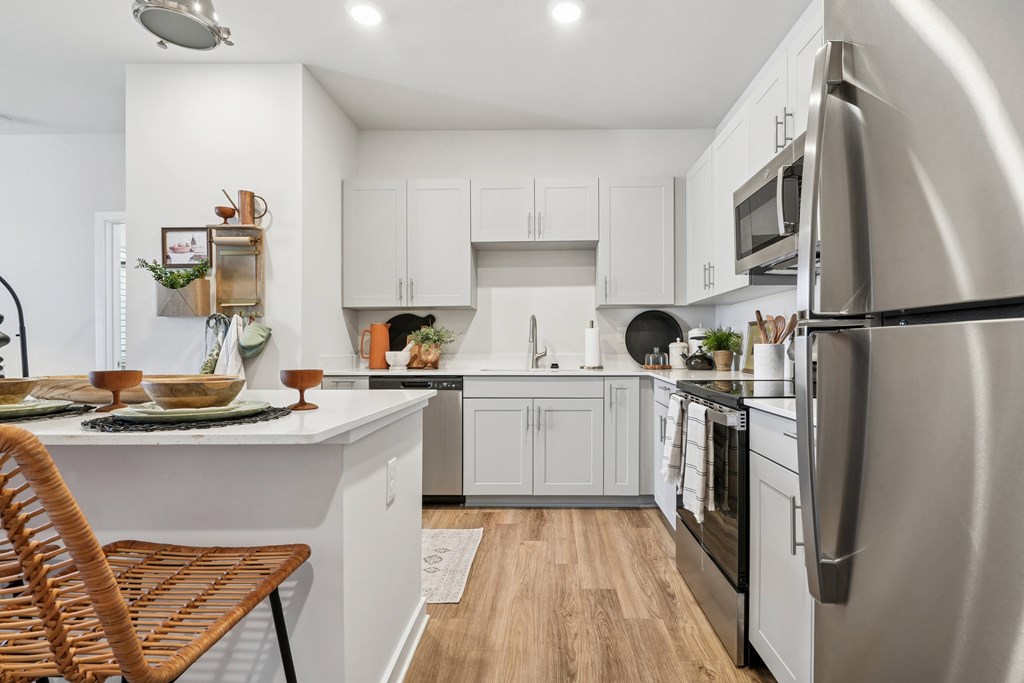 A modern kitchen with a refrigerator on the right and a chair on the left.