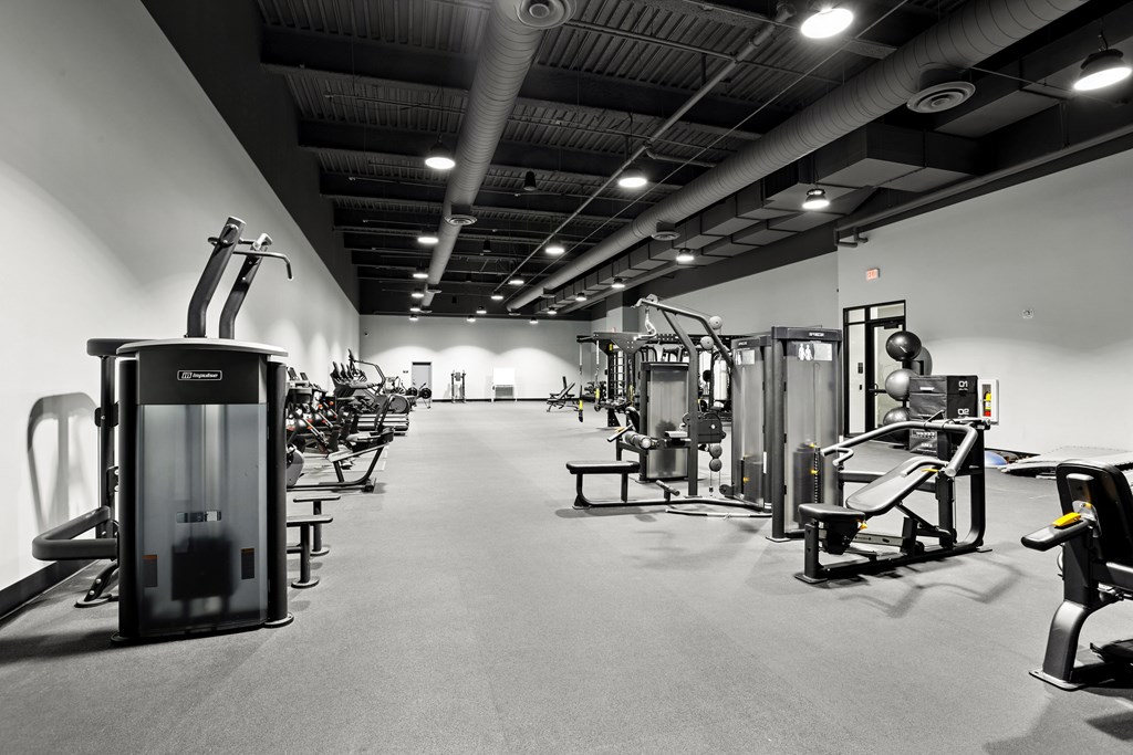 A black and white image of a gym with various exercise equipment.