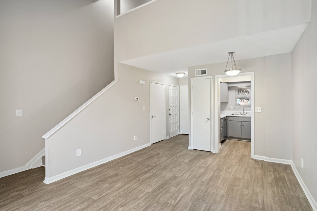 the living room and kitchen of a new home with white walls and wood flooring  at Emerald Bay, North Carolina
