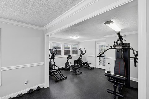 A black and white photo of a home gym with a treadmill, stationary bike, and other equipment.