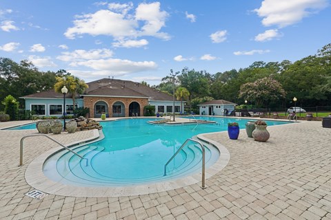 A swimming pool surrounded by a brick patio and a house in the background.