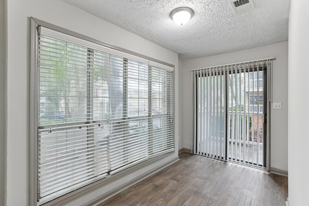 A room with a sliding glass door and a window with blinds.