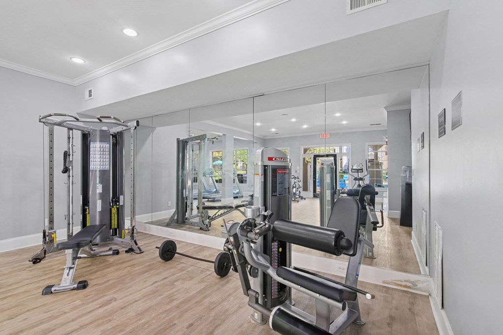 A gym with a mirror, weights, and exercise equipment.