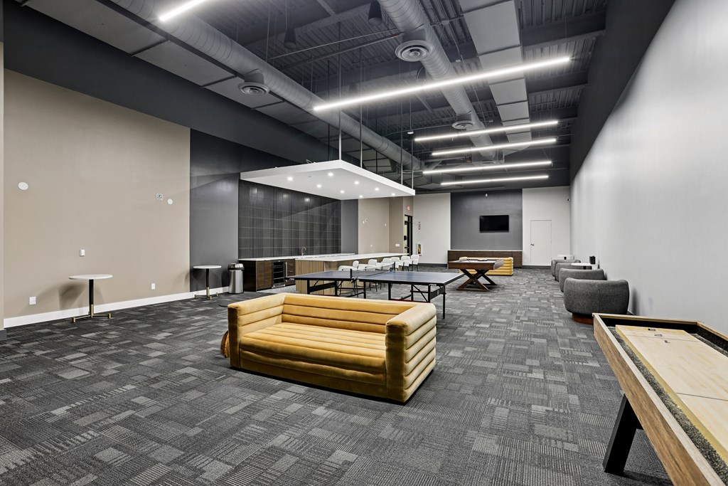 A modern office space with a long table and chairs, a couch, and a ping pong table.