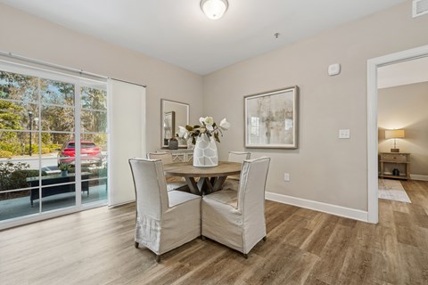 A dining room with a table set for two and a view of a parking lot outside.