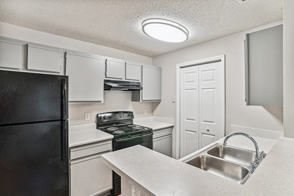 Apartment kitchen with black appliances and white cabinets at Wellington Farms, Charlotte, North Carolina