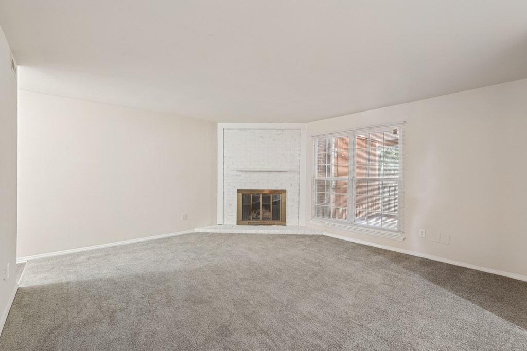 A large empty room with a fireplace and a window.