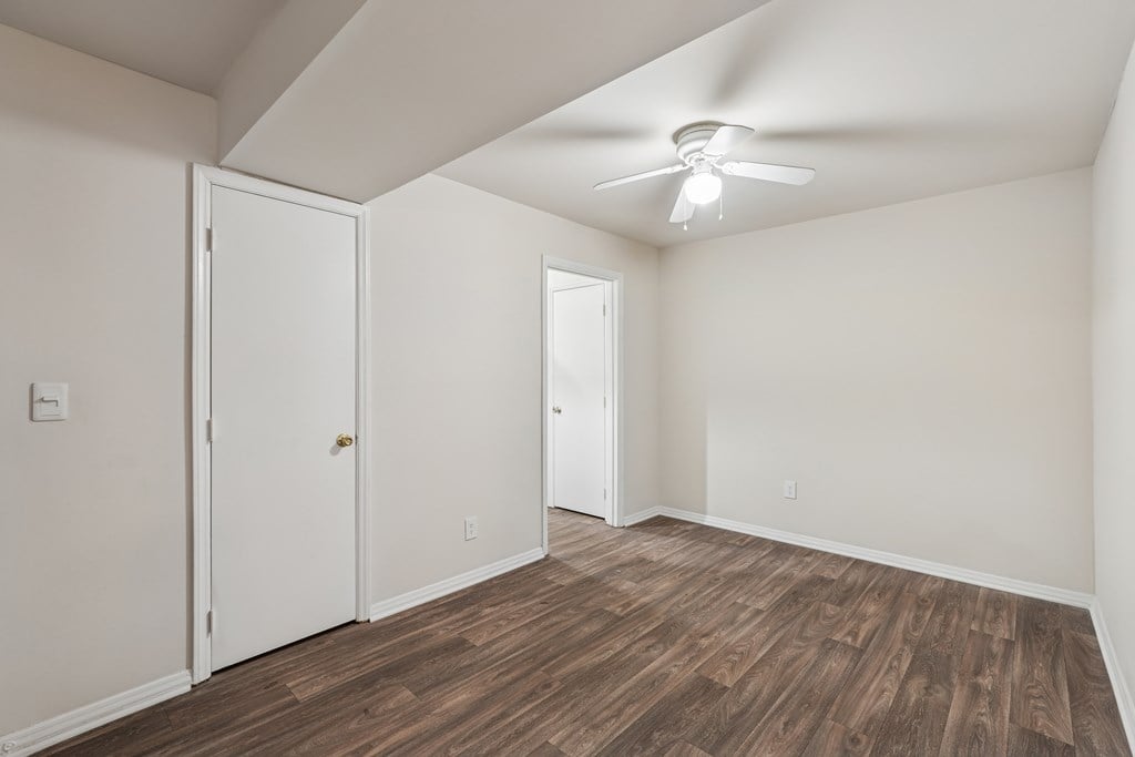 A room with a ceiling fan and wood flooring.