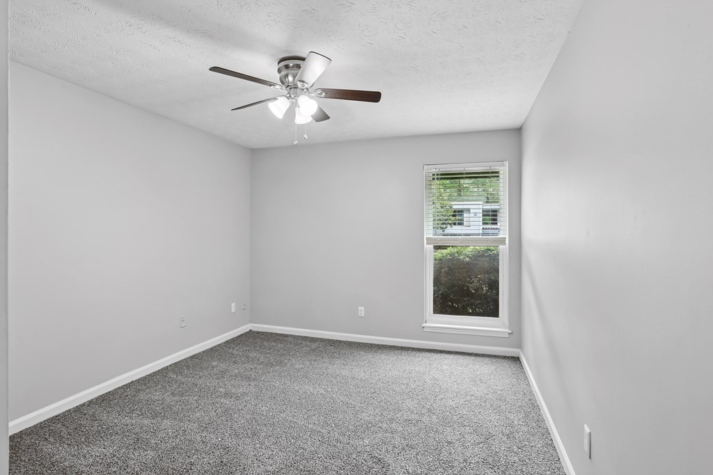 A room with a ceiling fan and a window.