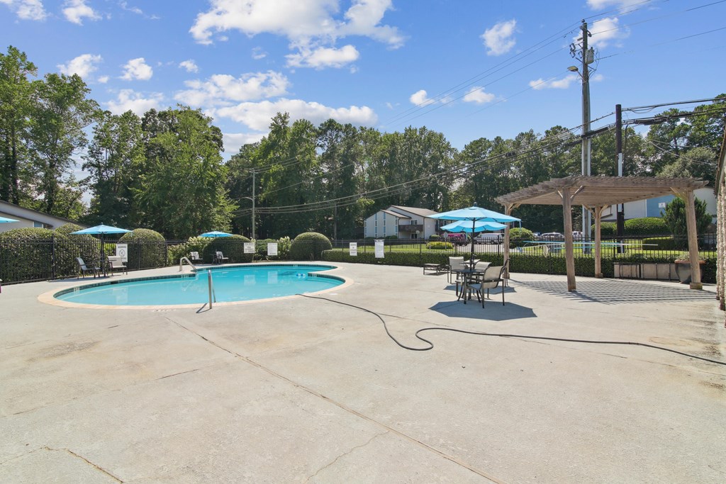 A pool with a hammock and umbrellas.